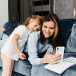 mamma e bambina sul divano con smartphone