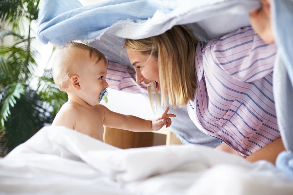 bebè che gioca con la mamma sotto le coperte