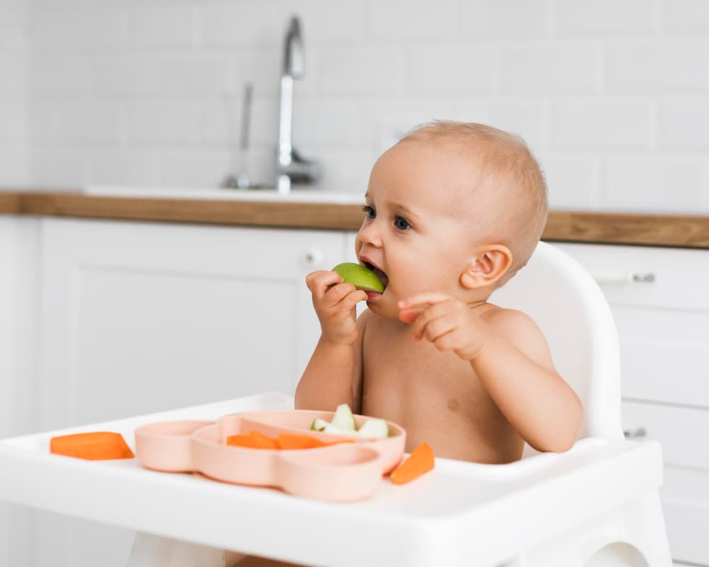 bambino che mangia frutta sul seggiolone