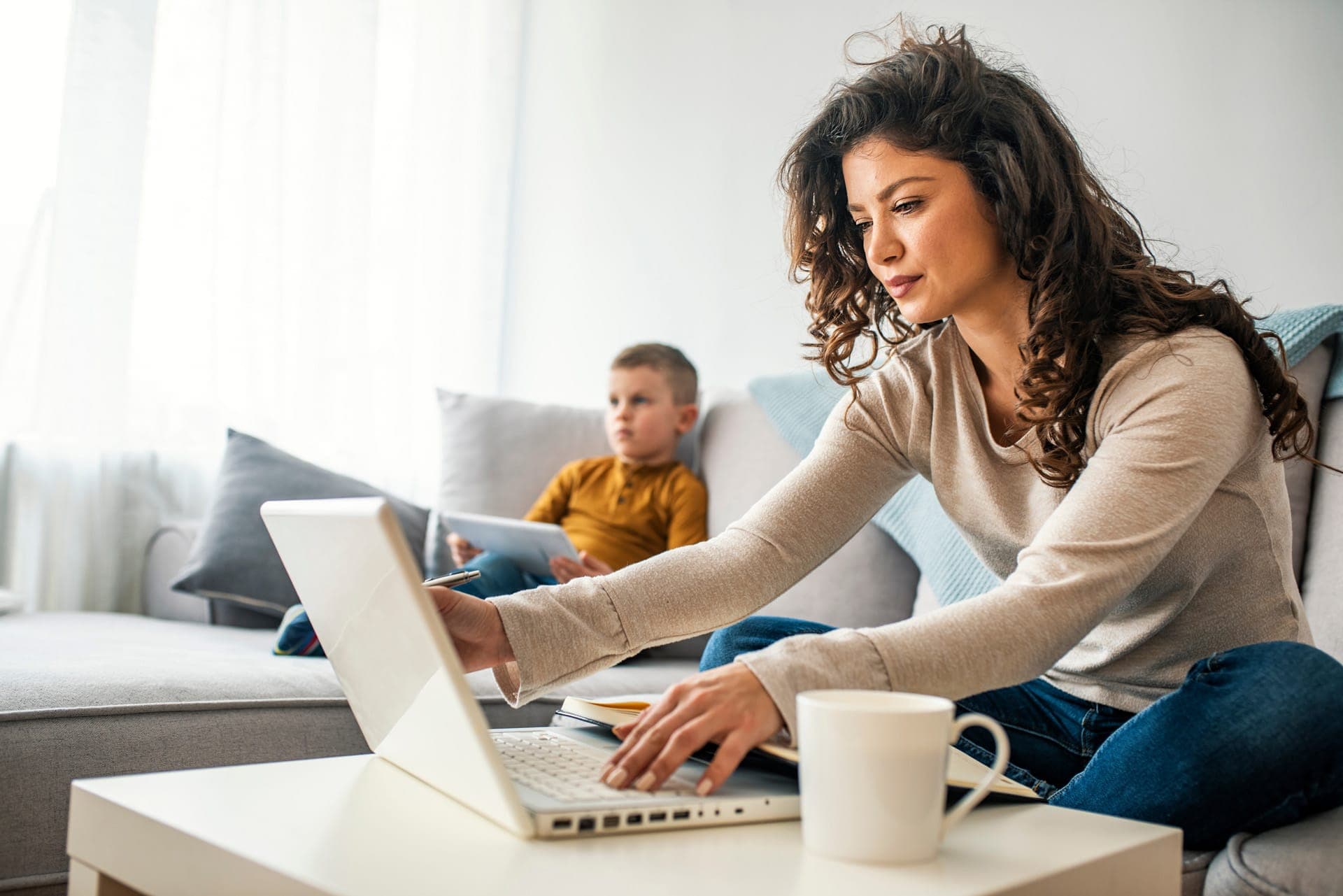 giovane madre che lavora mentre il figlio guarda la tv