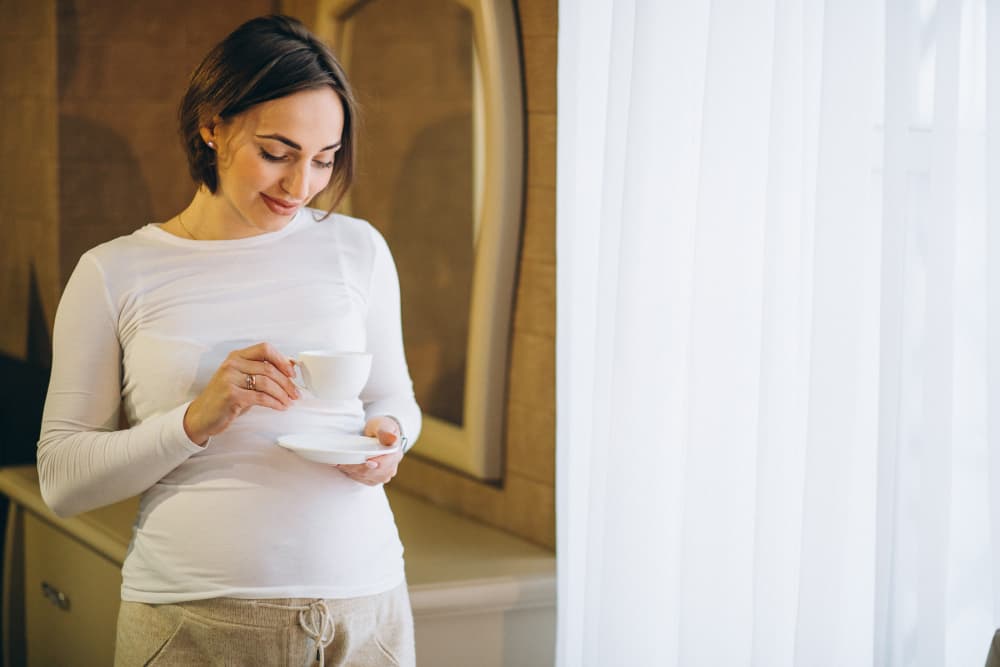 donna incinta con tazza di caffè