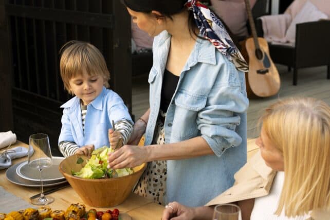 Bambino a tavola che si serve insalata