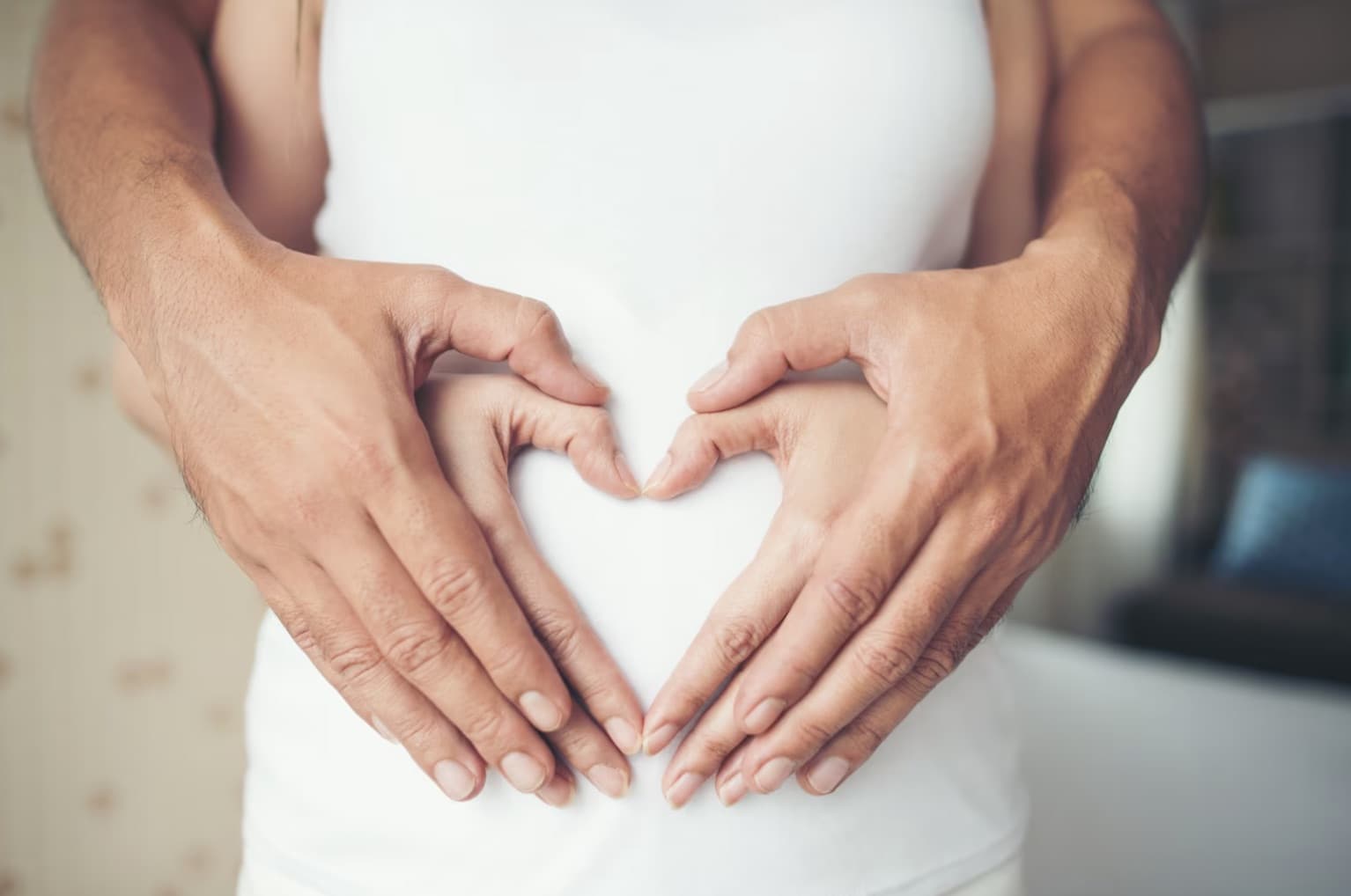 donna incinta con marito che tiene mani sulla pancia