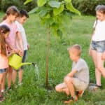 bambini che piantano un albero nel prato