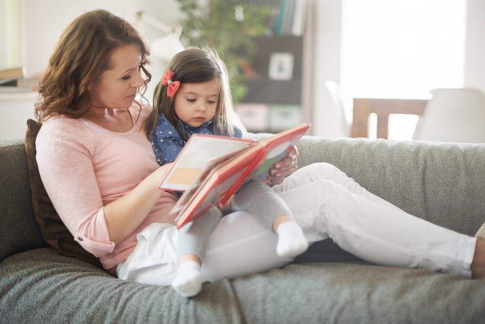 mamma che legge un libro con in braccio la bambina