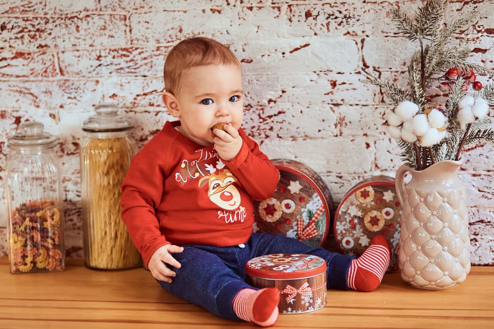 bambino in posizione seduta che mangia un biscotto