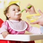 bambina che mangia la pappa nel seggiolone