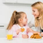 mamma e figlia in cucina con biscotti e succo di arancia