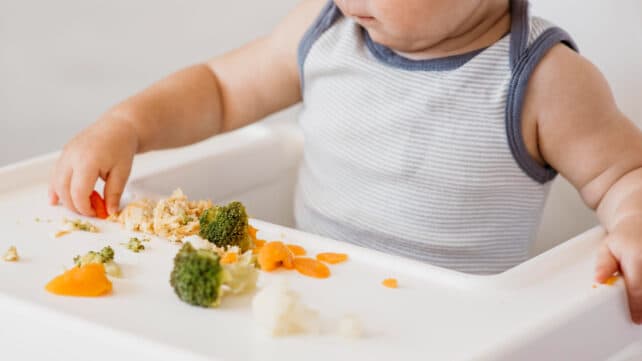 bambino che mangia sul seggiolone