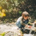 bambino che beve acqua ad una sorgente