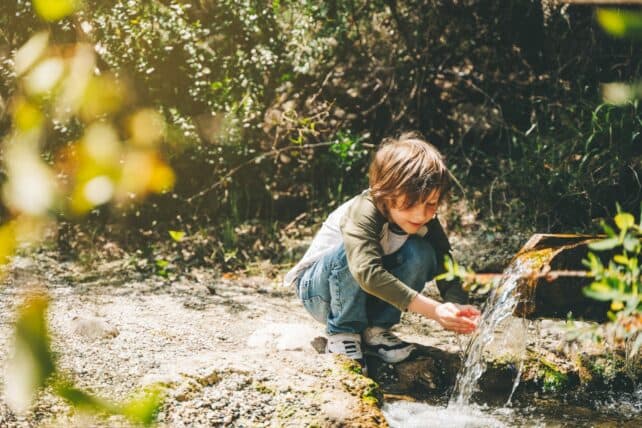 bambino che beve acqua ad una sorgente