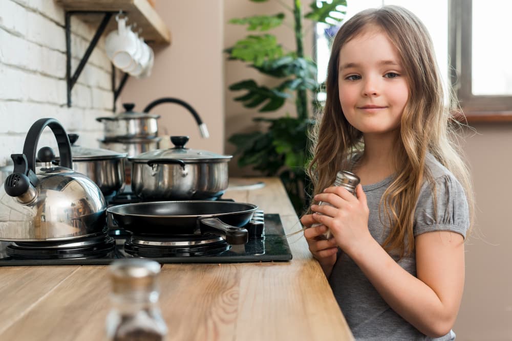 bambina in cucina accanto ai fornelli