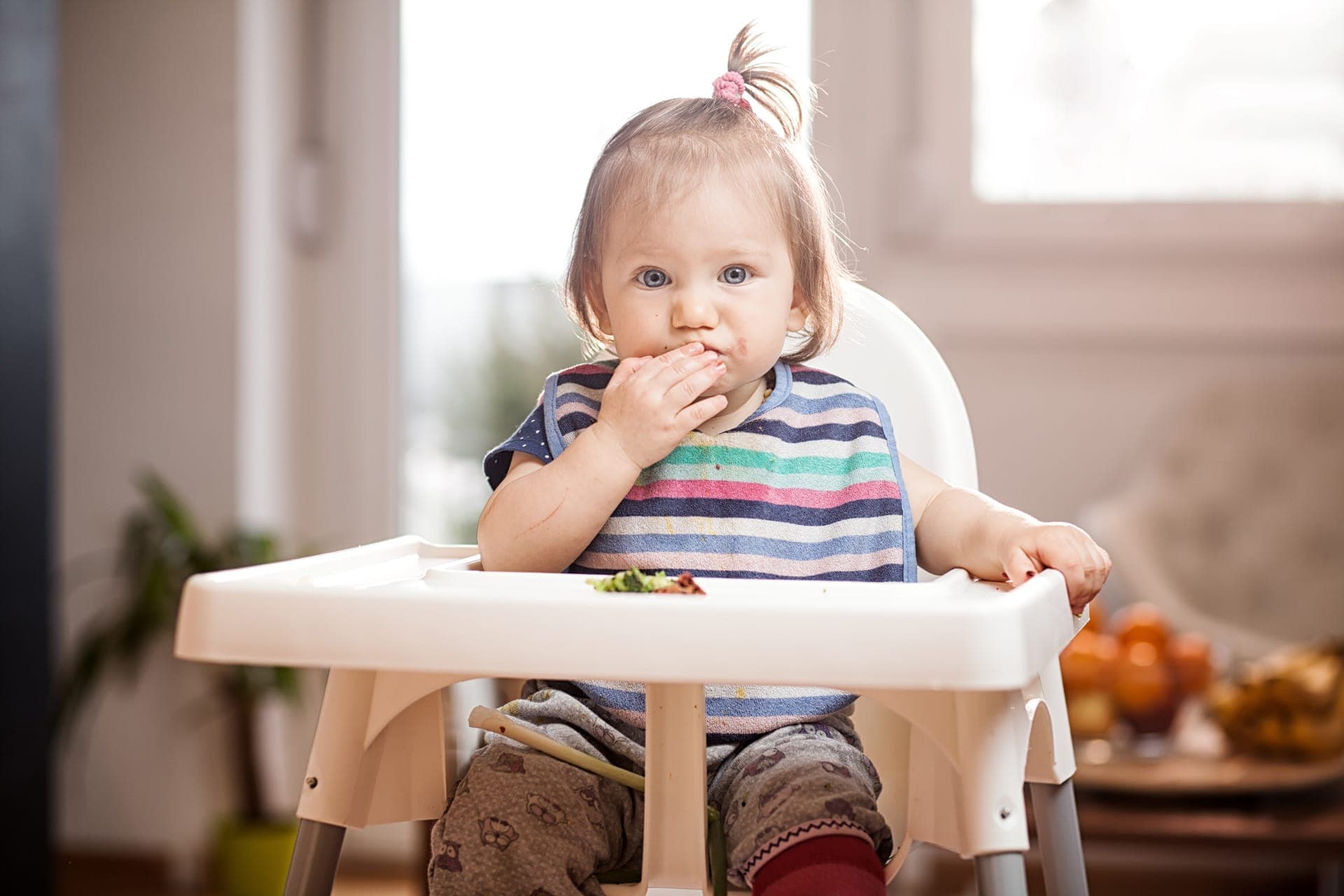 bambina sul seggiolone che mangia