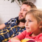 bambina che guarda la TV assieme ad un genitore