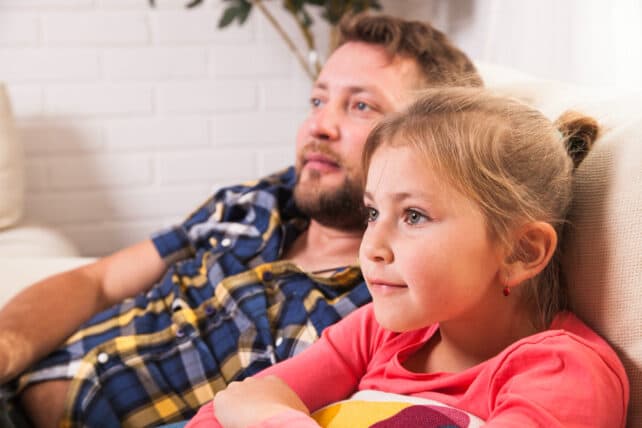 bambina che guarda la TV assieme ad un genitore